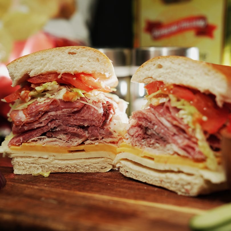 A large, sliced sandwich from The Great Wazu, filled with meats, cheese, lettuce, and tomatoes.